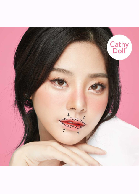 Woman with makeup lines on her face against a pink background, featuring the 'Cathy Doll' brand.